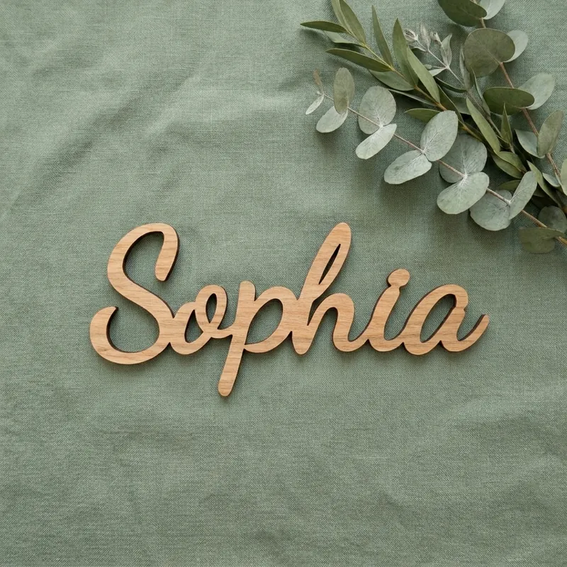Wooden name sign reading Sophia in the Swirly font, on sage linen with eucalyptus